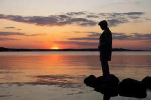 Pessoa contemplando o pôr do sol em reflexão sobre como lidar com a saudade de quem morreu